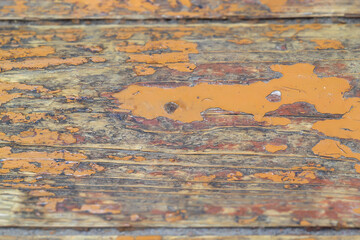 Wooden rustic floor with peeling orange paint close-up