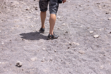 Tourist in sandals walking along the footpath to the top of Vesuvius volcano on a hot day, Mount Vesuvius, Italy.
