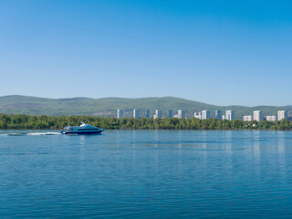 The boat sails along the Yenisei River. View of the city of Krasnoyarsk. Summer sunny day. Clear sky