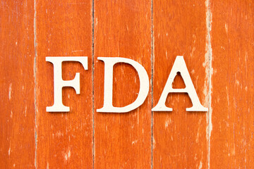 Alphabet letter in word FDA (abbreviation of food and drug administration) on old red color wood plate background