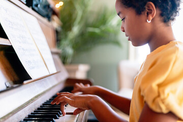 Musical education. Happy black girl playing the piano © NDABCREATIVITY