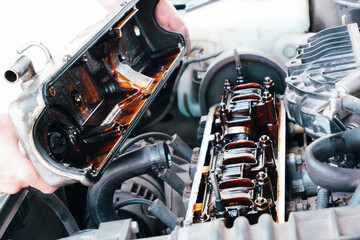 Car repair. The use of poor quality oil in the engine. Deposits of tar from oil on the inside of the engine. The mechanic examines the head on the internal combustion engine