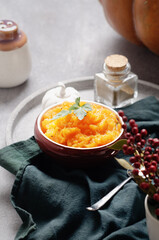 Purea of pumpkin in a brown bowl on grey light background.