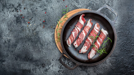 chevapchichi with rosemary in Cast iron pan. Kofta kebab. raw sausages of ground beef or pork with spices wrapped in bacon. Sausages. banner, menu, recipe place for text, top view