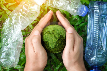 top view of hands holding protect the earth from plastic bottle waste on a green background....