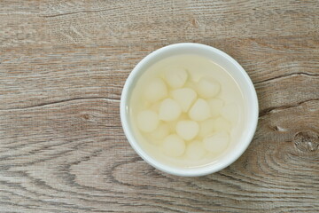 pickled single garlic with salt water in cup on table
