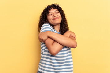 Young mixed race woman isolated on yellow background hugs, smiling carefree and happy.