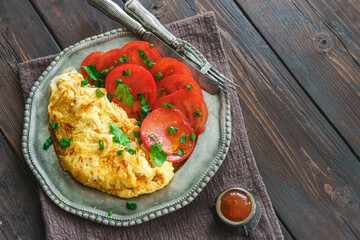 Scrambled eggs with tomatoes on rustic table top view