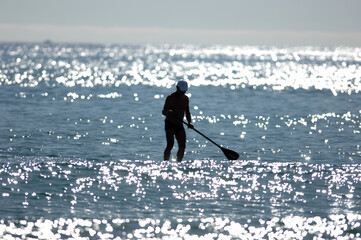 A stand up paddler in the twilight in the coastal water of Finestrat-Spain.