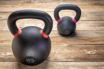 two heavy iron kettlebells on a rustic wood background, weight training and  fitness concept