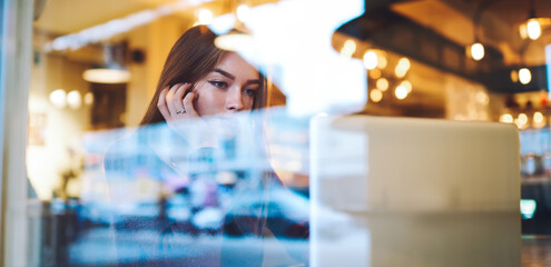 Pensive woman with hand on cheek using laptop