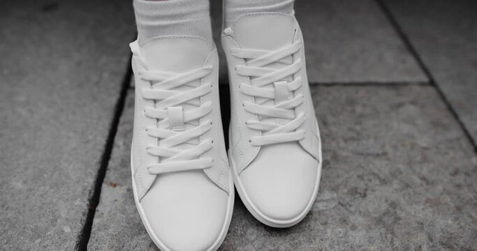Unrecognizable woman wearing white sneakers on the legs