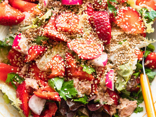 Fresh summer healthy fiber protein vitamin salad in bowl with strawberries, lettuce, tuna, tomatoes