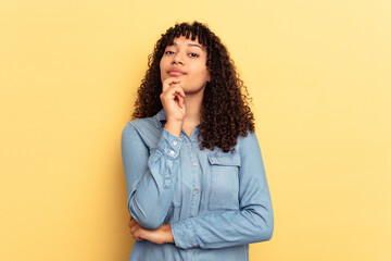Young mixed race woman isolated on yellow background suspicious, uncertain, examining you.
