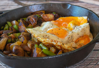 Fried eggs with potatoes and vegetables in a pan