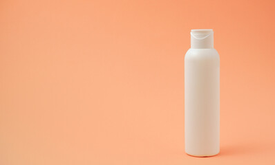 White pure suntan lotion, body cream, shampoo or sunscreen bottle for packaging mockup. White bottle and orange background. Minimal summer skincare and sun protection concept. Place for your text.