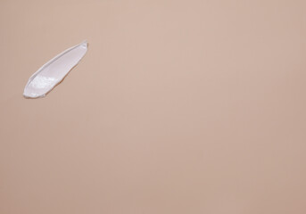 Creamy texture. A smear of white hand cream on a beige background.