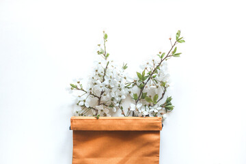 Sprig of cherry blossom in a orange canvas bag on a white background. Eco concept, copy place, flat lay