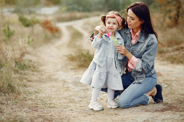 Mother with little daughter playing in a autumn field