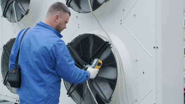 Technician uses a thermal imaging infrared thermometer to check the condensing unit heat exchanger