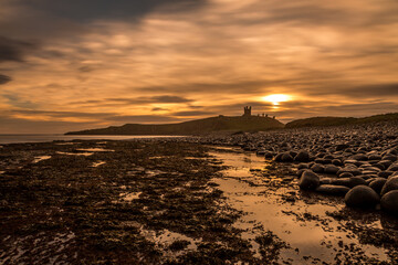 Obraz premium Dunstanburgh Castle in Northumberland, England, just after sunrise