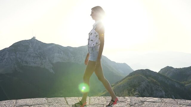 Caucasian young woman walking on top of a mountain in summer at sunset. Outdoor, lifestyle