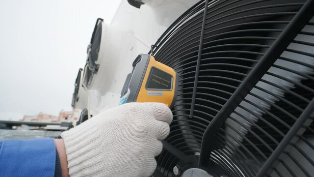Technician uses a thermal imaging infrared thermometer to check the condensing unit heat exchanger