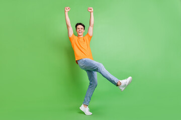 Full body photo of cheerful triumphant luck man raise hands winner hooray isolated on green color background