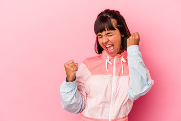 Young mixed race woman isolated on pink background raising fist after a victory, winner concept.