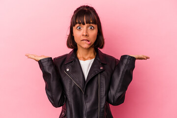 Young mixed race woman isolated on pink background confused and doubtful shrugging shoulders to...