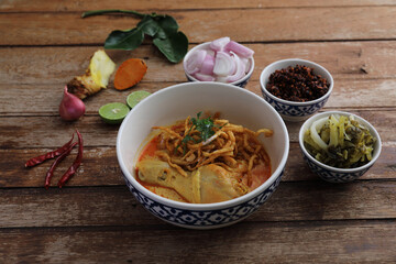 Local northern Thai food Egg noodle curry with chicken on wood background