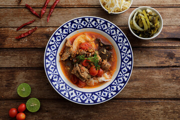 Local northern thai food Rice noodles with pork in spicy soup in wood background