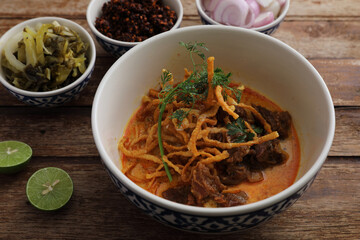 Local northern Thai food Egg noodle curry with beef on wood background