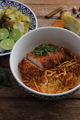Local northern Thai food Egg noodle curry with fried pork on wood background