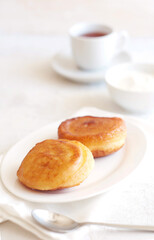 Pancakes are in a plate on the table, behind sour cream and tea. Nice breakfast