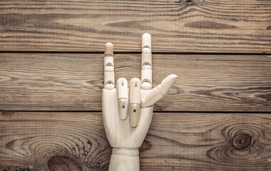 Wooden hand shows rock gesture on wooden background