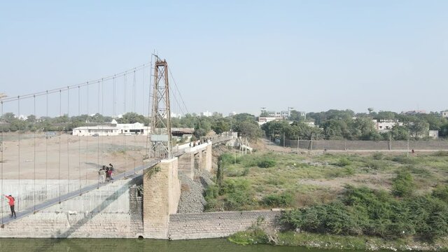 Drone flies high in the sky above floating clouds. Below, overlooks an impressive view of the Hanging bridge near machhu dam, Aerial. 4K