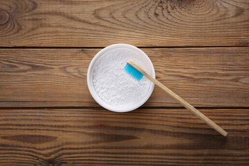 Eco bamboo toothbrush and tooth powder on wooden background