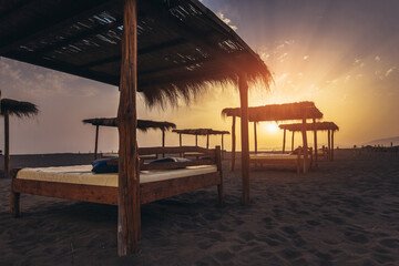 Sandy beach with sun beds at sunset