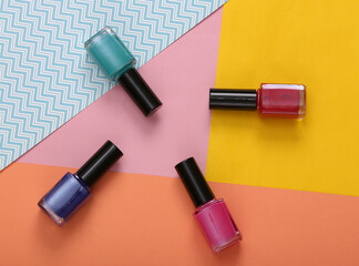 Obraz premium Bottles of colored nail polish on a colored background. Top view