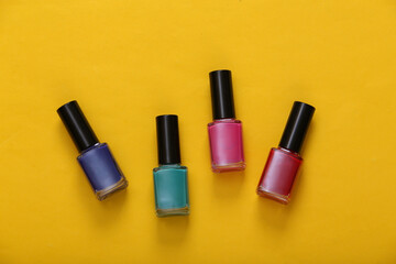 Obraz premium Bottles of colored nail polish on yellow background. Top view