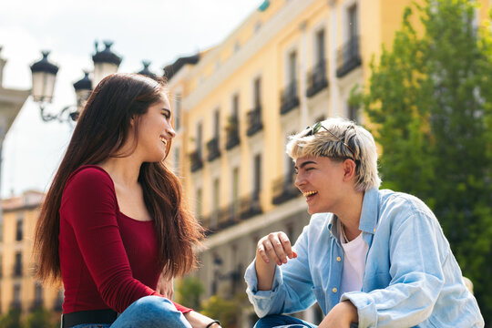 Two young girls sitting in a bench and talking