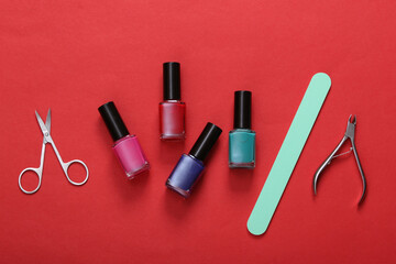 Manicure accessories. Nail polish bottles, scissors and nail file on red background. Top view. Flat lay