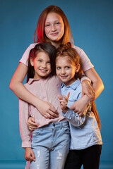 three kids girls standing together on blue background