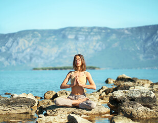 Fototapeta na wymiar Morning maditation and yoga in beautiful mountains landscape, healthy woman sitting in asana Namaste Lotus pose with eyes closed