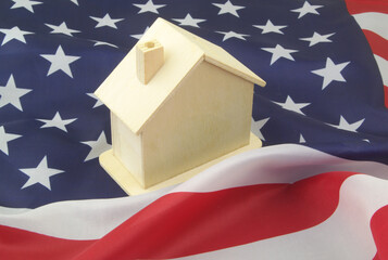 Real estate in USA concept. Wooden house on flag of United States. 