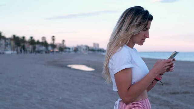 Portrait attractive young woman using smartphone surprised texting browsing messages online.
Woman Using Her Mobile Phone. On The Beach. Barcelona, Calafell, Spain.