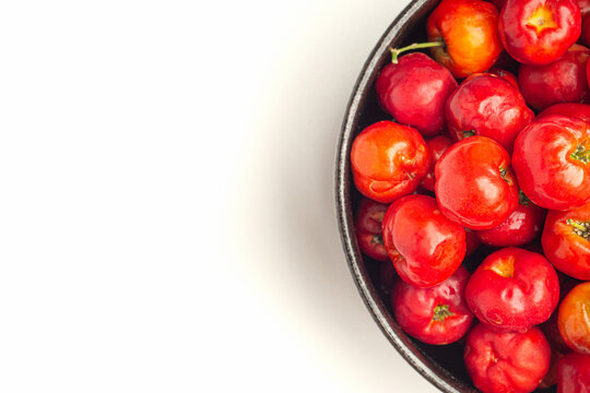 Red Acerola Cherries Fruit In A Ceramic Bowl Isolated On A White Background. High Vitamin C And Antioxidant Fruits. Close-up. Space For Text. Concept Of Healthy Fruits