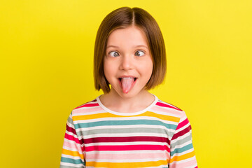 Photo portrait little girl with bob hairstyle fooling showing tongue grimacing isolated vibrant yellow color background © deagreez