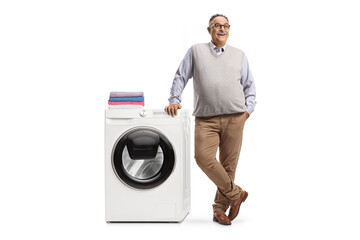 Smiling mature man leaning on a washing machine